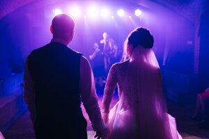 beautiful_couple_newlyweds_stand_with_their_backs_hold_hands_look_friends_who_perform_song_them_their_wedding_day_enjoy_music